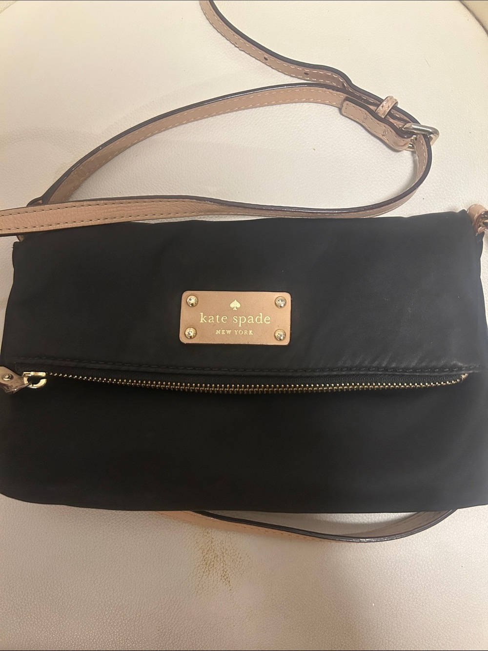 kate spade black crossbody with tan strap and gold-tone plaque